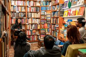 A group of teenagers sit together in a cozy bookstore