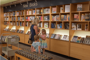 A woman and her two young children browse books at the New Book Shelf in the Canton Public Library
