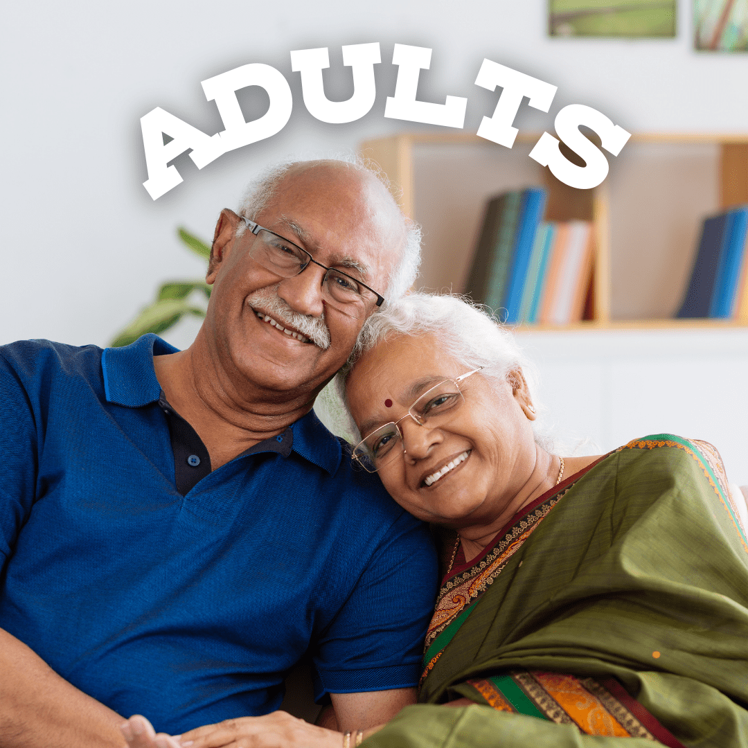 A senior Indian man and woman lean together and smile at the camera