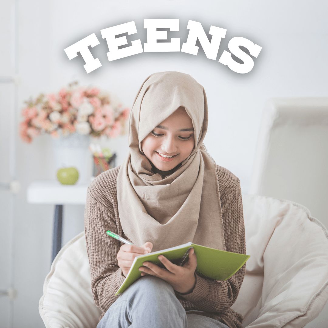 A Muslim teenage girl smiles as she writes in her notebook in a comfy chair